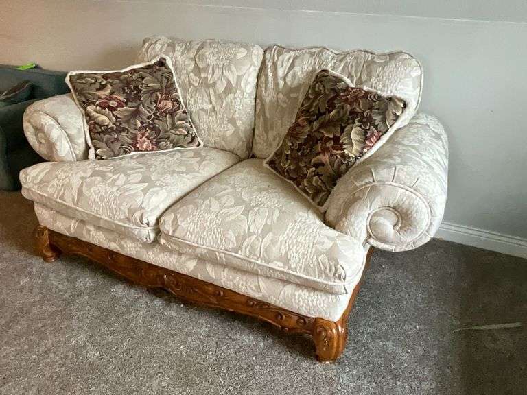 Upholstered loveseat with ornate feet, damage to one foot with throw pillows