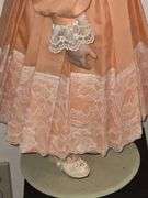 Porcelain doll in peach dress on stand, 24" T