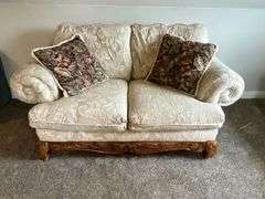 Upholstered loveseat with ornate feet, damage to one foot with throw pillows