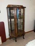Lighted curved front curio cabinet with glass shelves and mirrored back