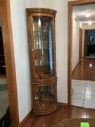 Lighted corner curio cabinet with glass shelves, paw feet, mirrored back