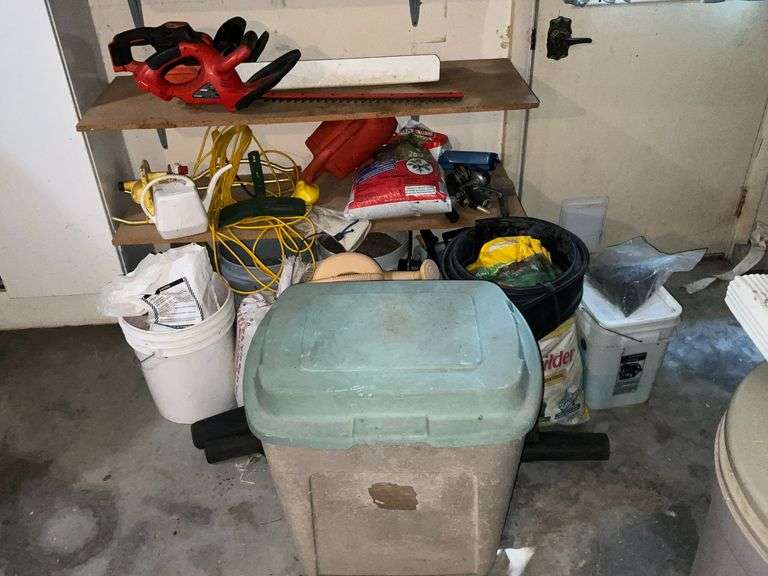 Bottom 2 shelves of garden supplies, hose, watering cans image