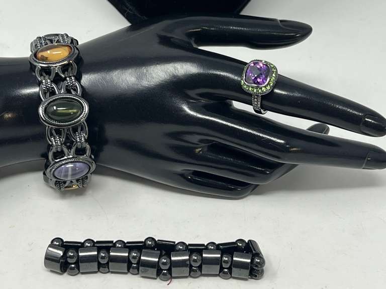 Ladies stretch bracelets, includes one with oval multicolored stones, a magnetic hematite bracelet, and a ladies fashion cocktail ring with a faceted amethyst colored stone surrounded by small green stones, see pictures for details. ￼ image