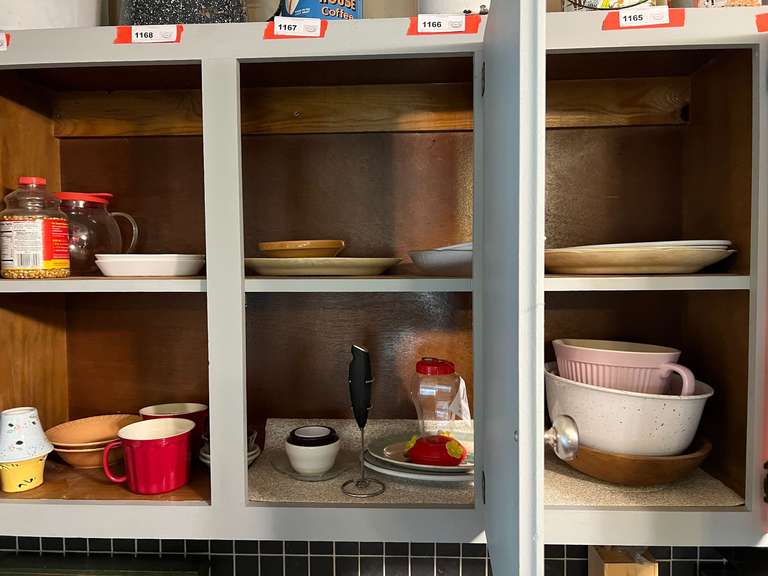 KIT…Cabinet lot marked 1170, includes all content of upper cabinets from edge of microwave to last cabinet past the sink. Items include mixing bowls, vintage platters, and assorted glassware and mugs. See pictures for details. image