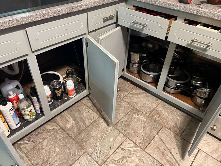 KIT… Cabinet lot marked 1179, includes all content from lower cabinets and drawers from edge of stove to edge of dishwasher. Items include cutlery, pots and pans, some cleaning supplies, and more. See pictures for details. image