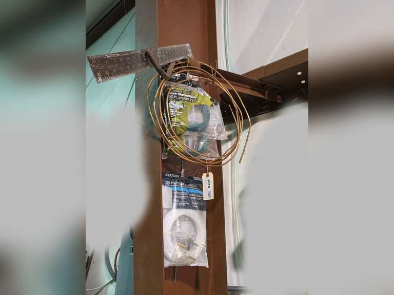 ALL ITEMS HANGING IN SHOP SUPPORT BEAM AREA MARKED 1018 INCLUDING SQUARE TOOL, COPPER TUBING, PAIR OF UNOPENED VINYL COATED WIRE CLOTHES LINES, AND UNOPENED 25-FT POLY TUBE ICE MAKER KIT image