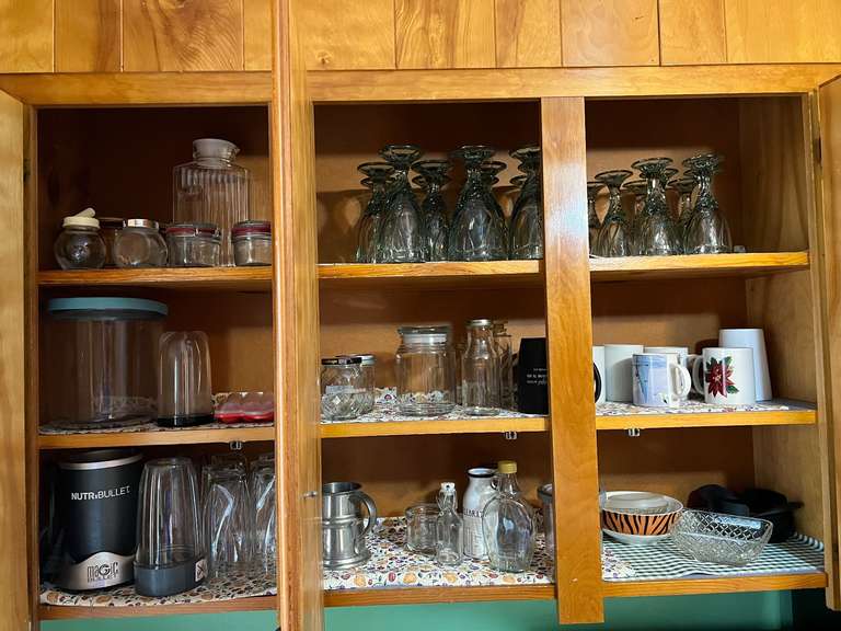 KIT… Upper cabinet lot marked 1078 to include contents from sink edge to refrigerator edge. Some contents include coffee mugs, assorted glassware, stemware, and more. See pictures for details. image