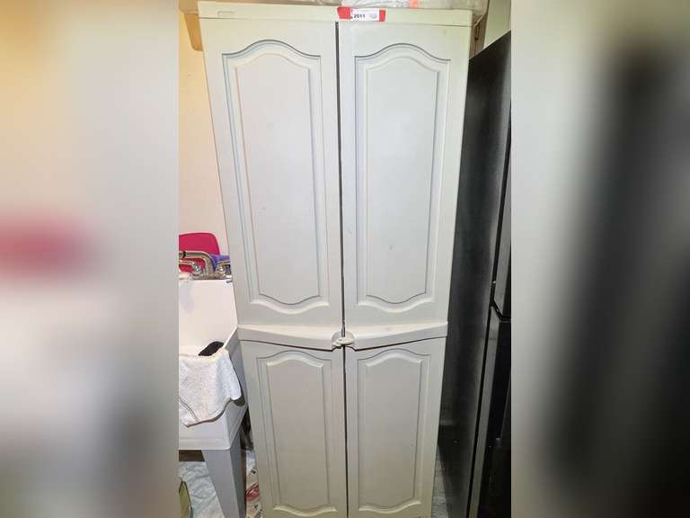 Laundry…Double door plastic storage cabinet with content. Some items include woven bread baskets, carafe, cake carrier, and more. Also includes tote on top of storage cabinet, see pictures for details. image