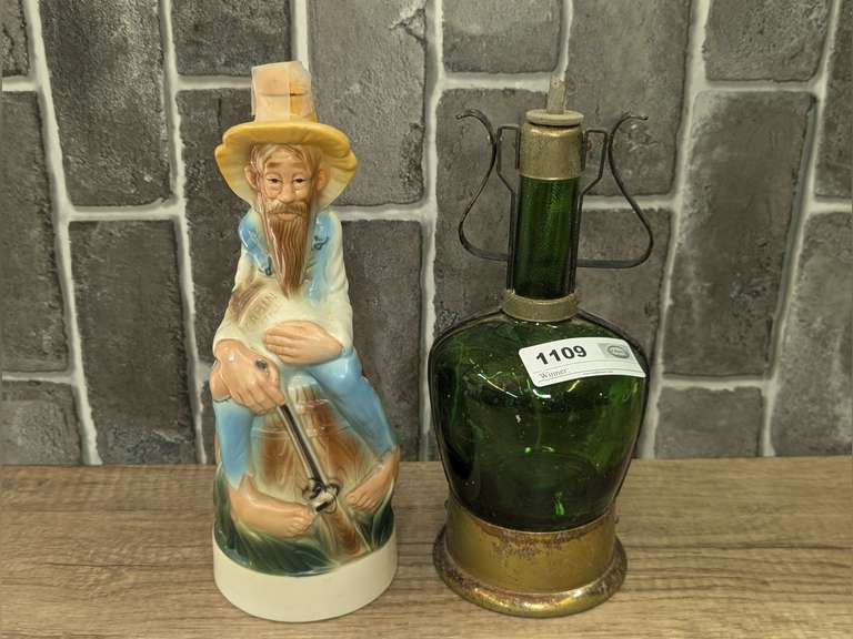 VINTAGE STITZEL WELLER DISTILLERY CABIN STILL COLLECTOR'S GALLERY 1969 DECANTER AND OLD GREEN GLASS BOTTLE WITH METAL MUSICAL FRAME CARRY HANDLE image
