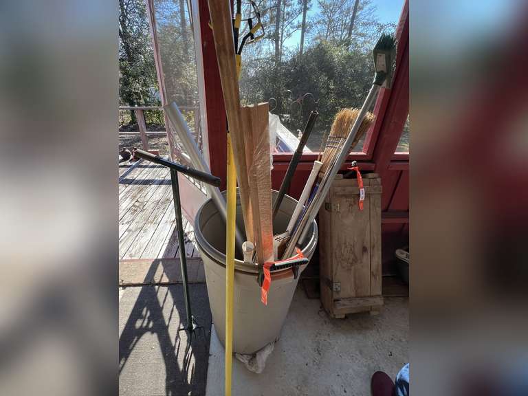 BP inside… Plastic garbage can of assorted items, includes a manual garden claw tiller, pole bulb changer, and more. Plastic can has a busted bottom, see pictures for details. image