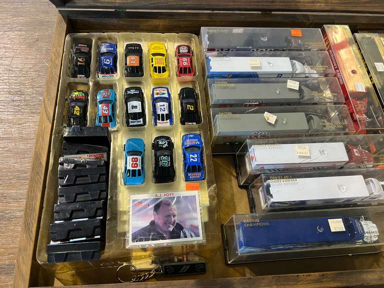 Shadowbox with large assortment of diecast racecar miniatures, diecast race car transport replicas, and more. The shadowbox trim needs reattaching, see pictures for details. image