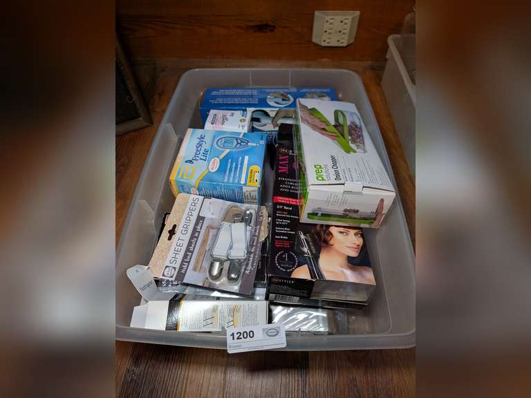 STORAGE TUB FILLED WITH NEW IN PACKAGE HOUSEHOLD ITEMS INCLUDING PREP SOLUTIONS ONION CHOPPER, IN STYLER ROTATING CURLING IRON, SUCTION CUP GRAB HANDLE, MARTHA STEWART DRESS BAG, SHEET GRIPPERS, AND MORE image