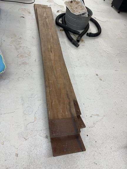 Two Wood Planks with Metal Brackets and Bucket with Vacuum Hose and Plumbing Parts image