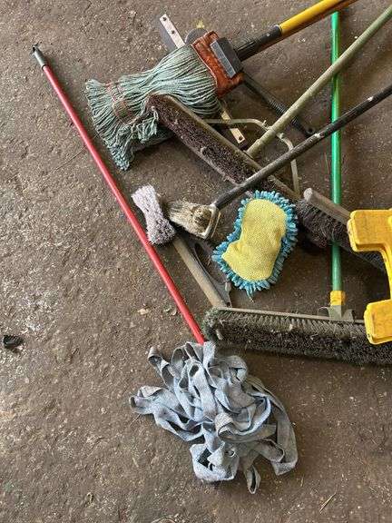 Assorted Cleaning Supplies: Mops, Brooms, and Caution Sign