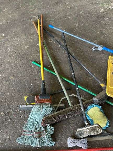 Assorted Cleaning Supplies: Mops, Brooms, and Caution Sign