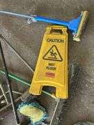 Assorted Cleaning Supplies: Mops, Brooms, and Caution Sign