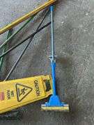 Assorted Cleaning Supplies: Mops, Brooms, and Caution Sign