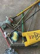 Assorted Cleaning Supplies: Mops, Brooms, and Caution Sign