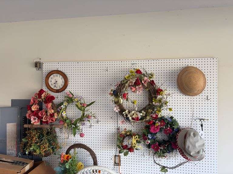 Wreaths & hats hanging on peg board image