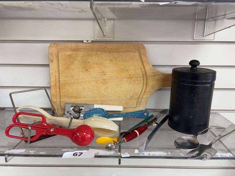 Miscellaneous kitchen utensils, black metal canister , and wooden cutting board image