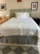 Full size bed with bedding. Upholstered headboard