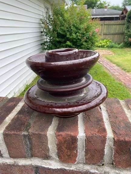 Outside decor, crock with chips on lip, insulator, concrete pedestal, 4 plastic pots with flowers