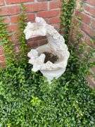 Outside decor, crock with chips on lip, insulator, concrete pedestal, 4 plastic pots with flowers