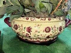 Needlepoint step stool, large floral arrangement in ceramic planter, sand dollar ornament
