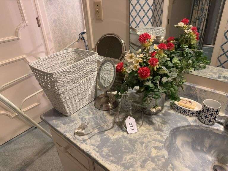Magnifying mirrors, wicker waste basket, floral arrangement, soap dish and cup ￼ image