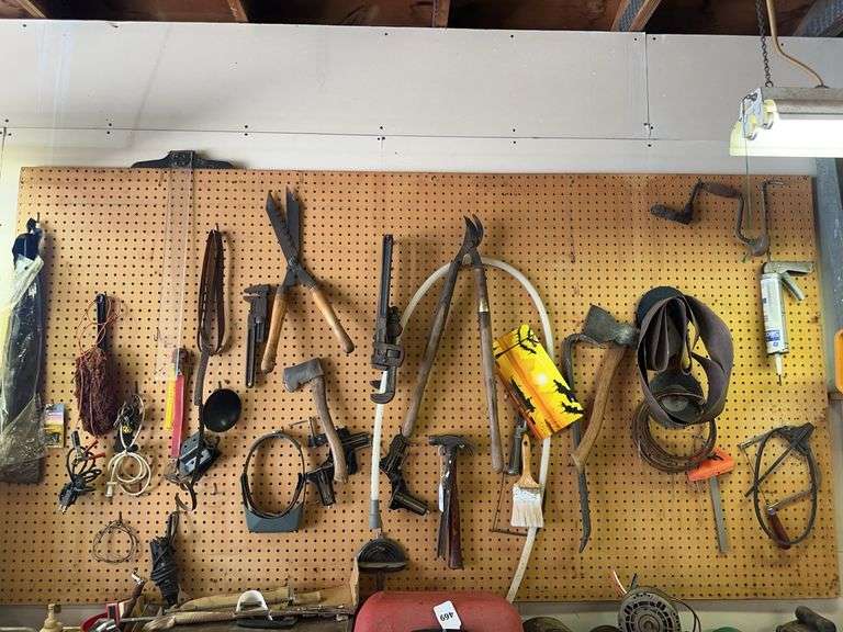 Content of wall peg board- pipe wrenches, axes, misc image