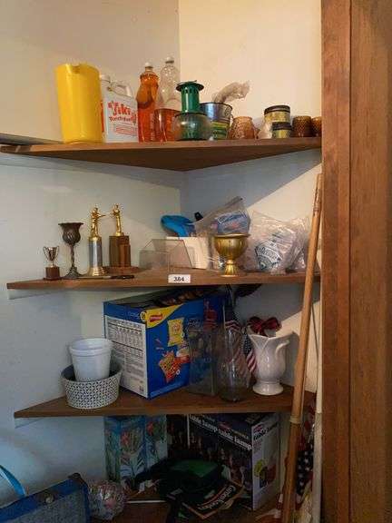 Corner shelves with miscellaneous items, candles, torch fuel, vases, outdoor table lights, garden kneelers, flags image