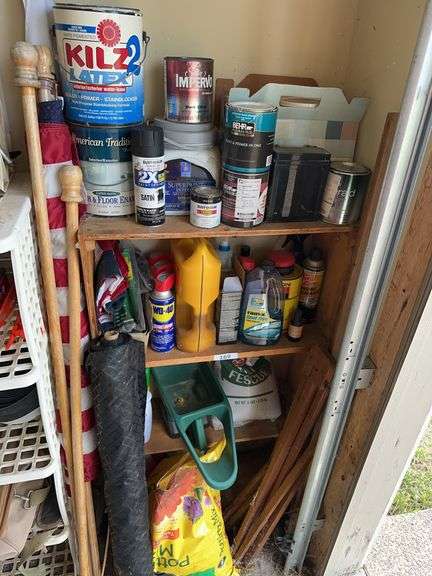 Shelf with contents: lawn care products, flags, soils, landscaping weed barrier, oil, paint image