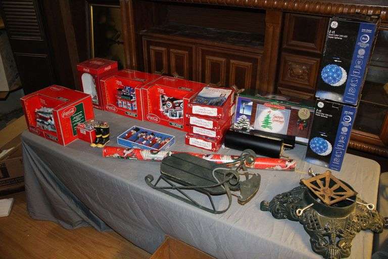Coca Cola Town Square Collection Village Decorations, Coca Cola Anniversary Clock, LED Icicle Clock, Wrapping Paper, Holiday Projector, Tree Stand, Coca Cola Figurines, Sled Decoration, and Nutcracker Figurines image