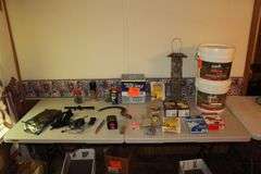 (2) Buckets of Base 2 Sealant, Bird Feeder, Rubber Tie Downs, Screws, Daisy 4x15 Scope, E Parker and Sons Fixed Blade Knife, Door Knobs, 18V Black and Decker Battery, and Misc.