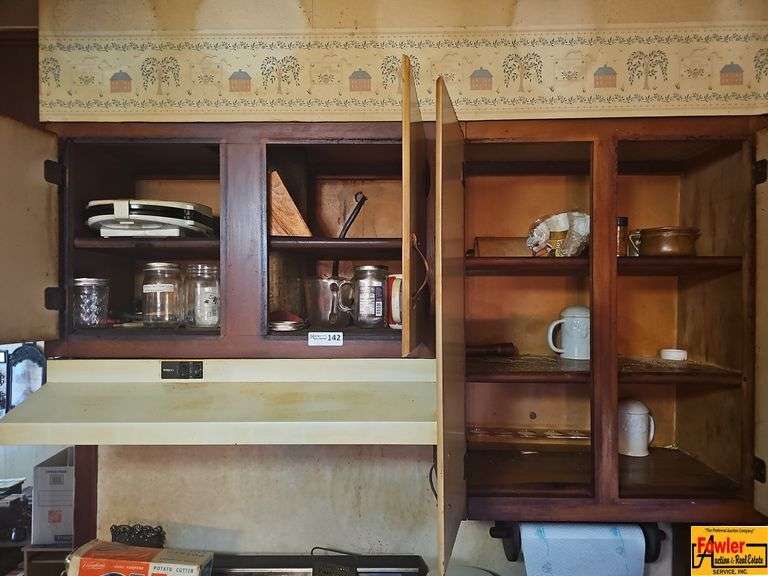 Various kitchen items including jars, a waffle maker, mugs, plates, and other kitchen wares. image