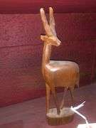 Various Decorative Items Including Faux Flower, Skull Wall Piece, Stick Dummy, 2 Head Figurines, Elephant Statue, 2 Antelope Statues, Golden Pumpkin, and Bird with Crown Statue