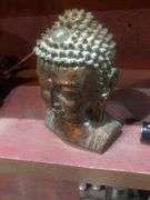 Various Decorative Items Including Faux Flower, Skull Wall Piece, Stick Dummy, 2 Head Figurines, Elephant Statue, 2 Antelope Statues, Golden Pumpkin, and Bird with Crown Statue