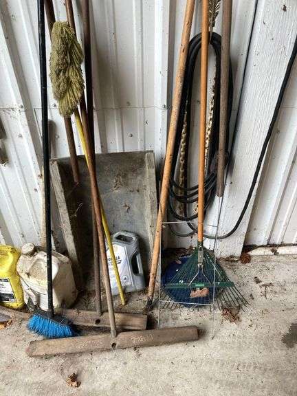 Contents of Wall Including Shovels, Brooms, Spud Bars, Pickax, and Rakes