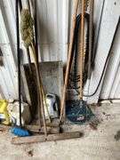 Contents of Wall Including Shovels, Brooms, Spud Bars, Pickax, and Rakes