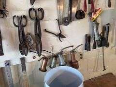 Tools hanging on wall, including wrenches, hammers, vice grips, saws, paint sprayers, bolt cutters, etc.