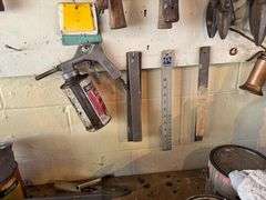 Tools hanging on wall, including wrenches, hammers, vice grips, saws, paint sprayers, bolt cutters, etc.