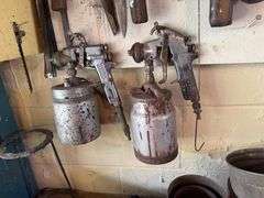 Tools hanging on wall, including wrenches, hammers, vice grips, saws, paint sprayers, bolt cutters, etc.