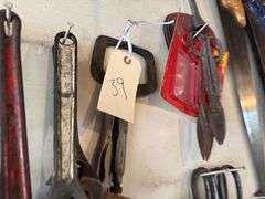Tools hanging on wall, including wrenches, hammers, vice grips, saws, paint sprayers, bolt cutters, etc.
