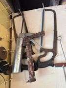 Tools hanging on wall, including wrenches, hammers, vice grips, saws, paint sprayers, bolt cutters, etc.