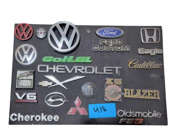 Assorted Vehicle Emblems on Wood Panel 24"x16" Ford, Volkswagen, K5 Blazer, Cherokee, Cherokee and others image