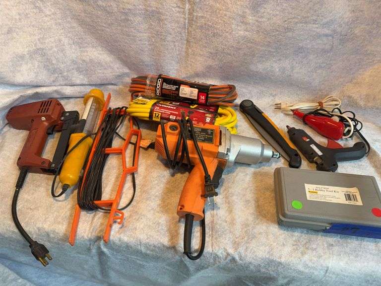 Two extension cords, one 12 gauge by 25 ft, one 14 gauge by 50 ft. Chicago electric 1/2-in impact wrench. Wen engraver. Hobby electric iron for wood burning and soldering. Ace electric glue gun. LED trouble light. Electric stapler. Fiskars folding limb saw. image