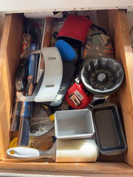 Contents of kitchen drawer includes mini baking pans, apple corer, Pampered Chef crinkle cutter, oven liners, tools, etc image