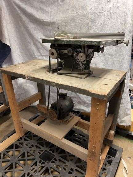8-In table saw on wooden stand. Delco motor 1 horsepower jigsaw on wooden stand, 18-in throat.  12-in square table. No names on either device image