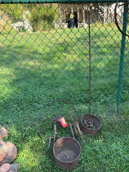 Metal yard art includes 2 mole traps, two kettles (one missing its bottom), 20” steel wheel image