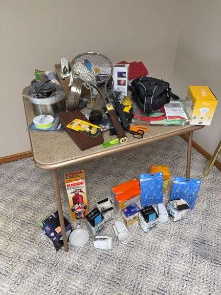 Card table and contents includes solar emergency radio, Zebco collapsible fishing rod, tennis racket, Banjo Bros bike bag, portable LP burner and more image